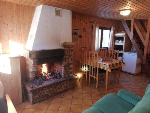 a living room with a fireplace and a dining room table at Location chalets in Le Thillot