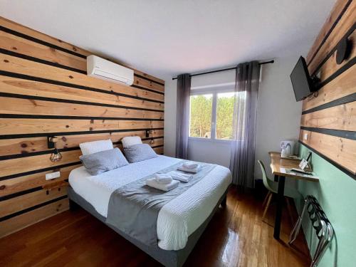 a bedroom with a bed with a wooden wall at Hôtel Paris Madrid in Lesperon