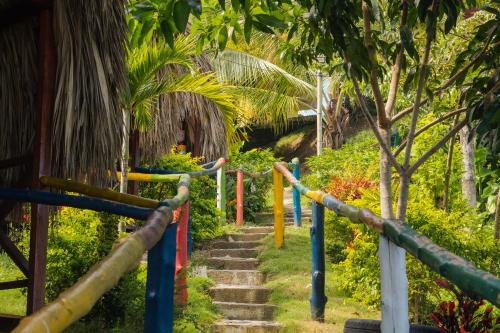 a set of stairs in a garden with colorful poles at Cabañas Orlando y Más Na' Tayrona in El Zaino