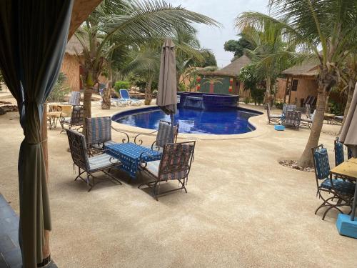un patio con sillas, una mesa y una piscina en Lodge des marseillais, en Ouoran