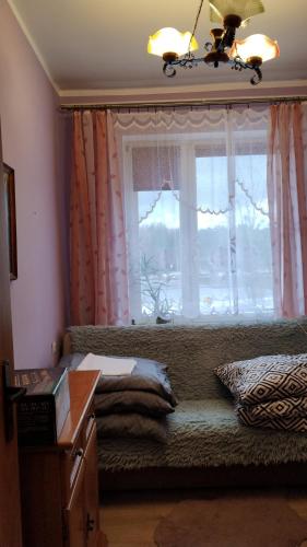 a bedroom with a window with a couch and a windowneau at Mieszkanko nad jeziorem in Rosnowo