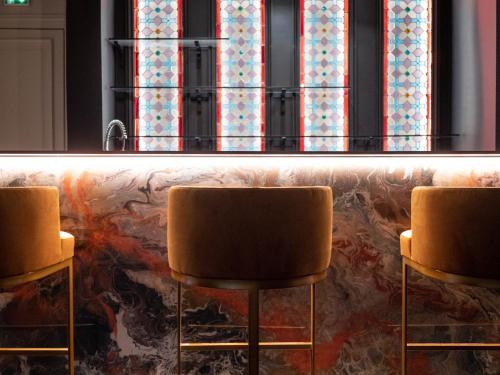 two chairs in front of a bar with windows at Hôtel Château Héloïse in Mérélessart