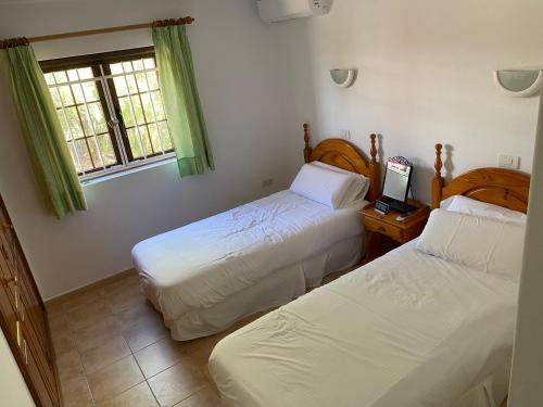 1 dormitorio con 2 camas y un ordenador portátil en una mesa en Las Brisas, Villa 98 en Playa Blanca