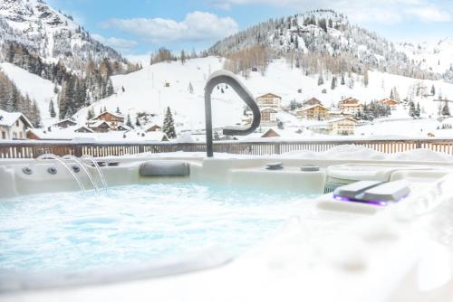 a hot tub with snow covered mountains in the background at HOTEL B&B MARILENA in Arabba