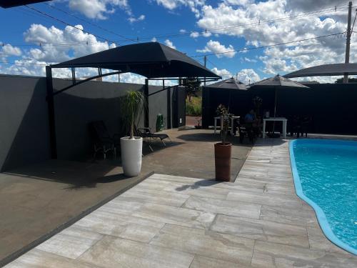 a swimming pool with an umbrella and a patio at JOTA Área de Lazer in Dourados