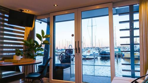 a view of a marina from a room with glass doors at Luxurious waterloft near beach and centre by Weltevreden Experience in Zeewolde