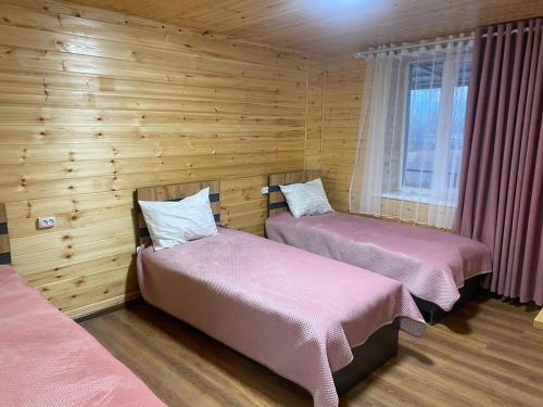 two beds in a room with wooden walls at Syi-Ordo Hotel in Pokrovka