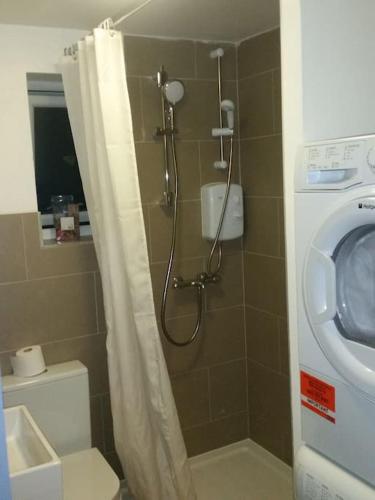 a shower in a bathroom with a washing machine at LOVELY 1 BED FLAT WITH GOOD TRANSPORT LINKS. in Morden