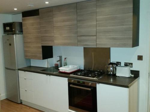 a kitchen with white cabinets and a stove top oven at LOVELY 1 BED FLAT WITH GOOD TRANSPORT LINKS. in Morden