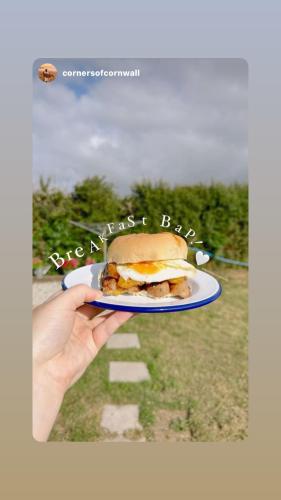 a hand holding a plate with a sandwich on it at Tregantle Farm Eco GLAMPSITE in Torpoint