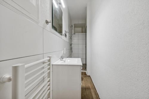 home2stay worker Apartments Metzingen في ميتزينغين: حمام أبيض مع حوض ومرآة
