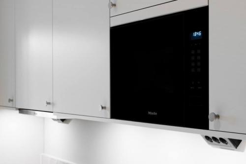 a microwave oven hanging on a kitchen wall at Chic Are Apt for 6 Ski-in-Ski-out with Sauna in Åre