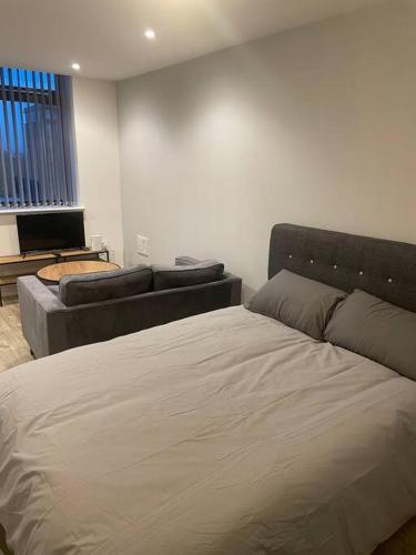 a bedroom with a bed and a couch at Stylish flat in Old Trafford in Manchester