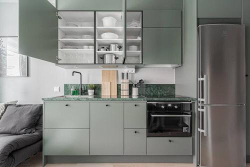 a kitchen with white cabinets and a stainless steel refrigerator at Beautiful and cozy Studio in a New building in Stockholm