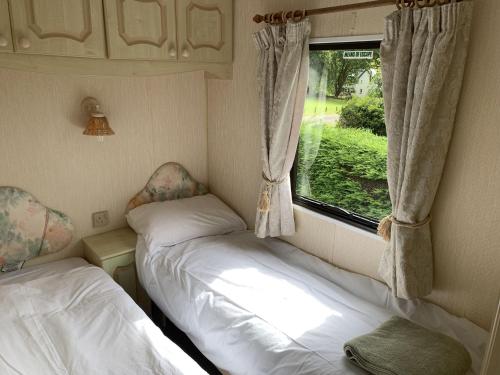 two beds in a small room with a window at Osprey Caravan in Onich
