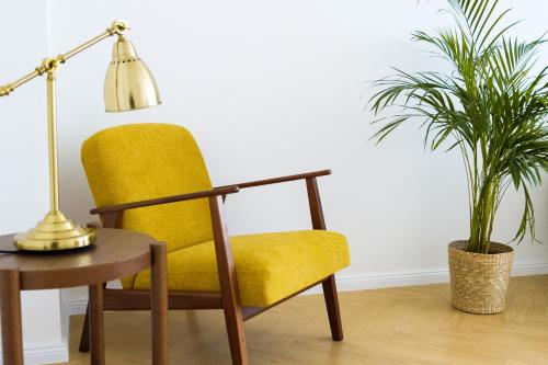 a yellow chair next to a table and two plants at Prorsus Design Apartments in Leipzig