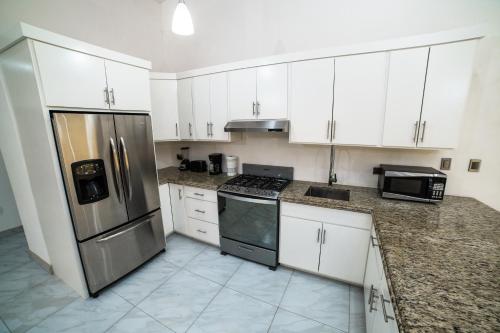 a kitchen with white cabinets and a stainless steel refrigerator at VILLA COSTA FELIX 1 in Puerto Peñasco