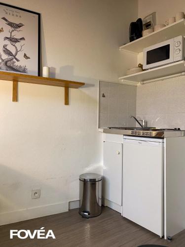 La cuisine est équipée d'un réfrigérateur blanc et d'un four micro-ondes. dans l'établissement Arés, à Caen