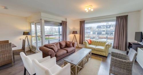 a living room with a couch and a table and chairs at La Cabane Penthouse in Nieuwvliet-Bad