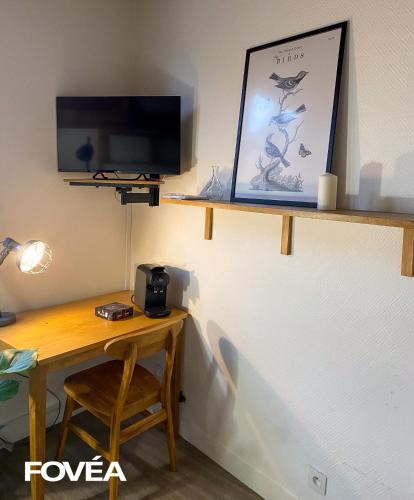 une pièce avec un bureau et une télévision sur un mur dans l'établissement Arés, à Caen