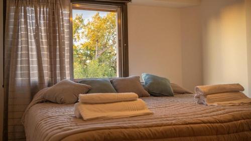 1 cama con almohadas en una habitación con ventana en Patagonia Residence en Trelew