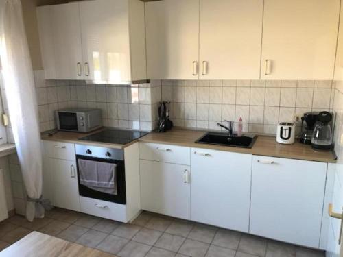 een keuken met witte kasten en een fornuis met oven bij Sol Ferienwohnung in Rodenbach