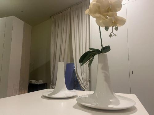 two white vases with flowers in them on a counter at Cinquecento B&B in Barcellona-Pozzo di Gotto