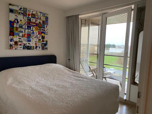 ニーウポールトにあるAppartement aan de yachthavenのベッドルーム1室(ベッド1台付)、スライド式ガラスドアが備わります。