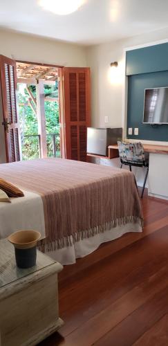 a bedroom with a large bed and a television at Pousada Tekoá Indiana in Cachoeiras de Macacu