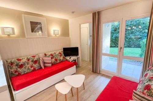 a living room with a red couch and a television at 6-person apartment with swimming pool tennis court and free parking REF25 in Le Touquet-Paris-Plage