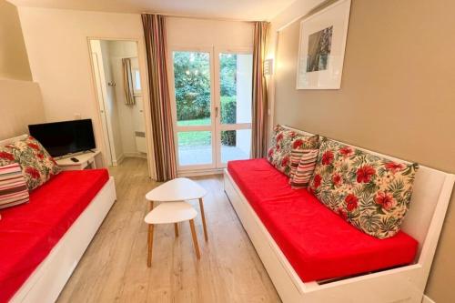 a living room with a red couch and a window at 6-person apartment with swimming pool tennis court and free parking REF25 in Le Touquet-Paris-Plage