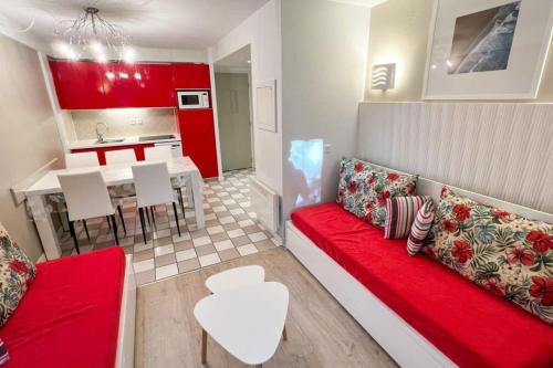 un salon avec un canapé rouge et une cuisine dans l'établissement 6-person apartment with swimming pool tennis court and free parking 25, à Le Touquet-Paris-Plage