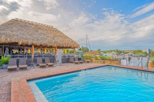 a pool with a straw umbrella and chairs and a bar at Heated Pool, Strong WI-FI, TV, Tiki Bar & Grill! in Sarasota