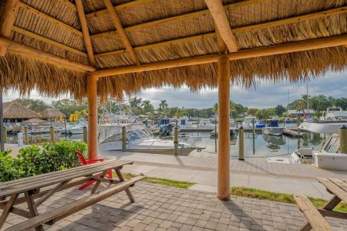 a picnic table under a straw umbrella with a marina at Heated Pool, Strong WI-FI, TV, Tiki Bar & Grill! in Sarasota