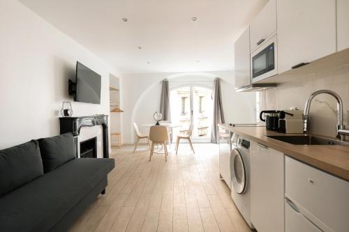 eine Küche und ein Wohnzimmer mit einem Sofa und einem Tisch in der Unterkunft Central Apartment in the heart of the Marais in Paris