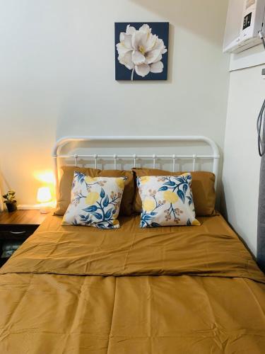 a bed with two pillows and a flower on the wall at EZ Cityscape Studio at Loop Towers Limketkai in Cagayan de Oro