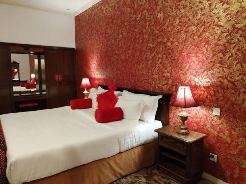 a bedroom with a bed with two red pillows at فندق روتانة الفرسان بالحمرا in Jeddah