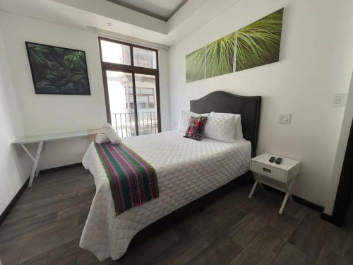 L1C 301 - Boutique apartment in Cayala for 4 guests في غواتيمالا: غرفة نوم مع سرير مع مكتب ونافذة