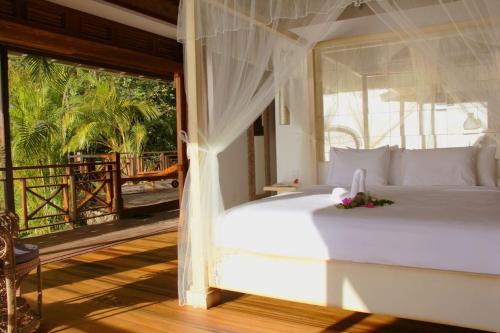 1 Schlafzimmer mit einem weißen Bett und einem Balkon in der Unterkunft Amazing 6 BR Ocen View Villa in Marigot Bay in Marigot-Bucht