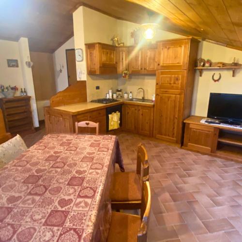 a kitchen with a table and a kitchen with wooden cabinets at La Baita sulla Neve - Posto Auto in Rocca Cinquemiglia
