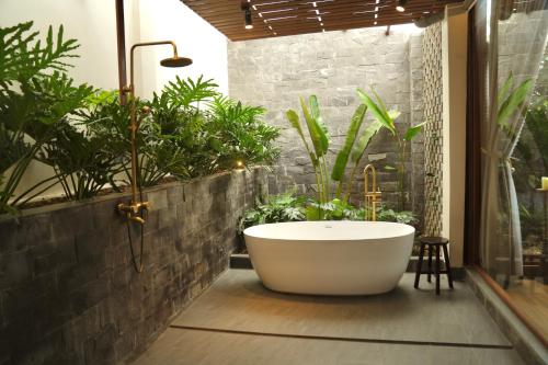 y baño con bañera y plantas. en Hapu Garden homestay, en Buôn Enao