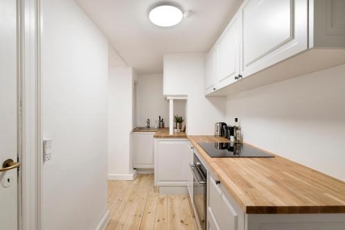 eine Küche mit weißen Schränken und einer hölzernen Arbeitsplatte in der Unterkunft Centrally located in Copenhagen in Kopenhagen