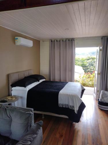 a bedroom with a bed and a couch and a window at Pousada Toscana Cambará in Cambará