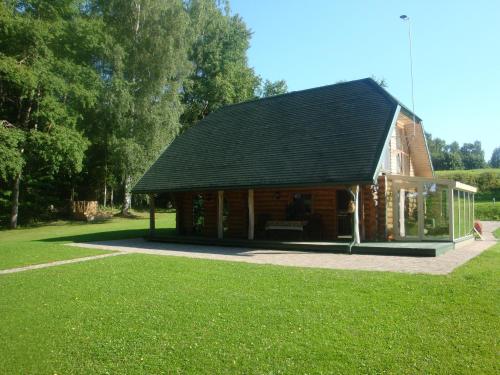 a log cabin with a black roof and green grass at Brīvdienu māja Ezerlīči in Korneti
