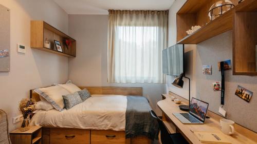 a bedroom with a bed and a desk with a laptop at Livensa Living Studios San Sebastián in San Sebastián