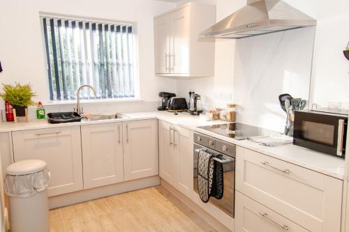 a kitchen with white cabinets and a sink and a microwave at City Centre - FREE PARKING, BUSINESS STAYS, FAMILIES, RELOCATORS in Durham