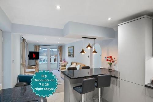 a kitchen and living room with a table and a couch at Miramont - Poolside Apartment in Guernsey
