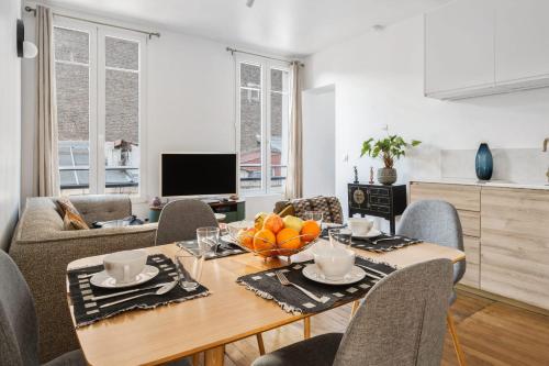 a dining room with a table and chairs and a television at Appartement Lutèce - Welkeys in Vincennes
