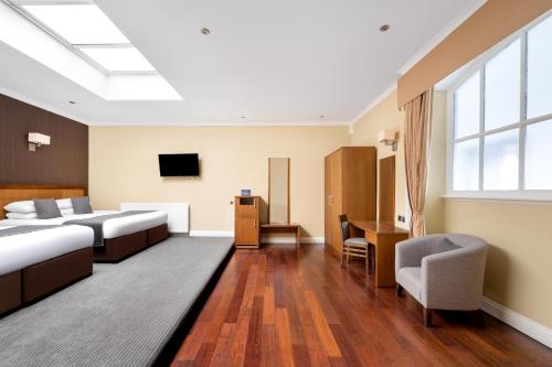 a hotel room with two beds and a desk at Royal Station Hotel- Part of the Cairn Collection in Newcastle upon Tyne