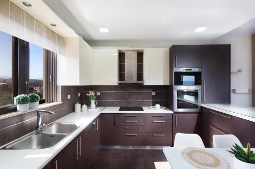 a kitchen with dark brown cabinets and white appliances at Villa Elisabeth View in Plataniás